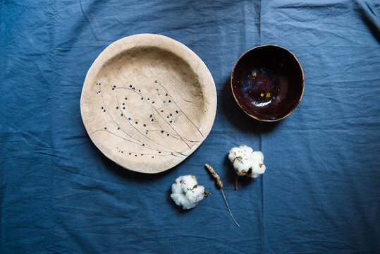 Plate, Bowl And Dried Flowers On Blue Textile