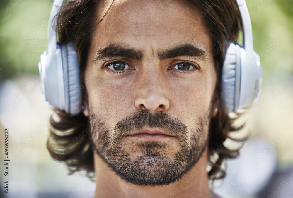 Wall mural Beast mode activated. Shot of a young man listening to music on his headphones outside in the park.