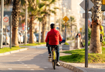 unknown senior man riding a bicycle on bikeway at sunset in La Serena