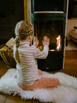 Girl getting warm at the fireplace