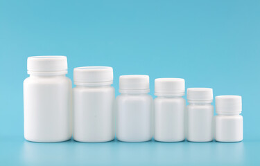 A row of decreasing white medicine bottles on a blue background