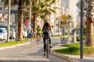 unknown woman riding a bicycle on bikeway at sunset in La Serena