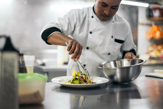 Hispanic chef plating a salad