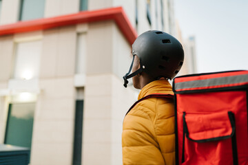 Black courier standing near house at delivery address