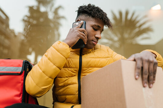 Delivery man checking box and making call to client