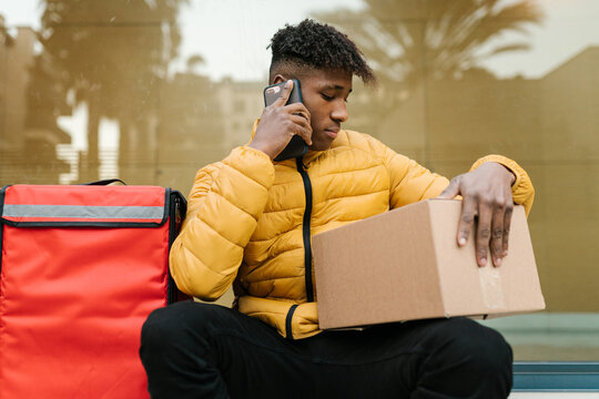Delivery man speaking with client via smartphone