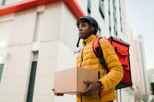 Black man with carton box and delivery bag