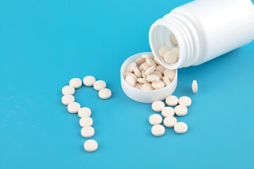 Pill bottle poured out of pills and composed of question marks