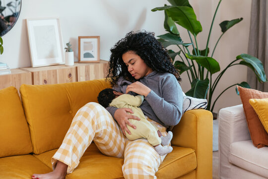 Mother breastfeeding baby on sofa