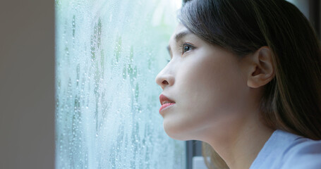 woman look through rainy window