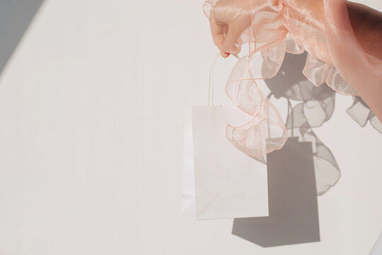 Crop tender woman with paper bag against wall
