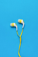 Classic headphones with a mobile phone wire on a blue background. Flat lay.