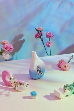 Acrylic painted unglazed ceramic vases on table against curtain background