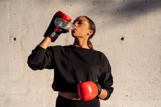 Hispanic boxer drinking water during training