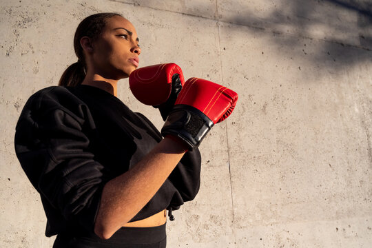 Thoughtful sportswoman in boxing gloves in city