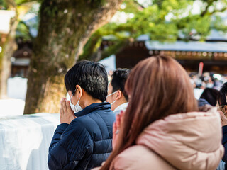 神社で手を合わせて参拝する人々