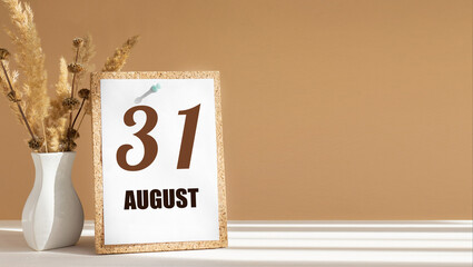 august 31. 31th day of month, calendar date.White vase with dead wood next to cork board with numbers. White-beige background with striped shadow. Concept of day of year, time planner, summer month