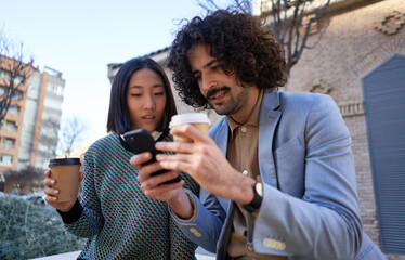Diverse colleagues using smartphone during coffee break