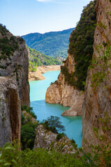 Fototapeta na wymiar Unique landscape of Mont-Rebei Gorge and Nogueira Ribagorcana River between steep rocky cliffs covered with greenery, Spain..