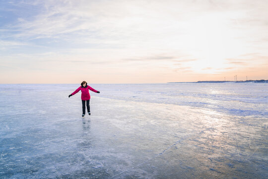 Woman Carefully Skating Outdoors on Frozen Lake in Winter at Dus