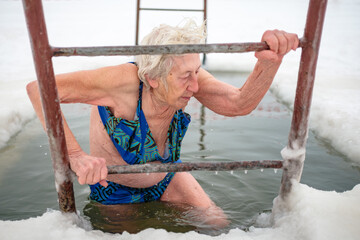 a woman ice-swimmer plunges into a ice-hole at frozen river