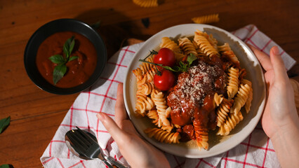 Top view, Female hands serving a plate of Italian fusilli pasta
