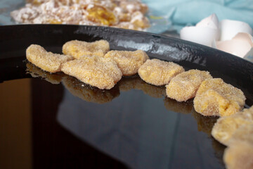 Chicken nuggets in breadcrumbs in a black cast-iron pan for baking