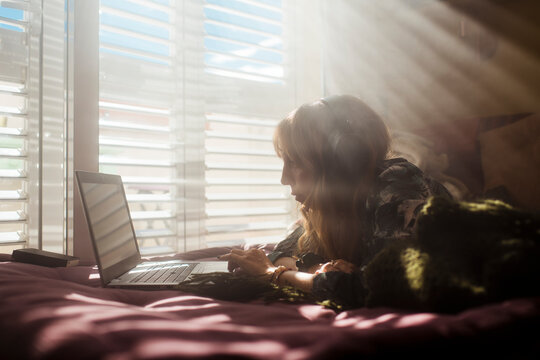 Woman using laptop and headset in the morning