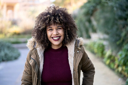 Delighted woman with curly hair in park