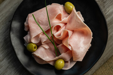 closeup of cooked ham in slices and green olives