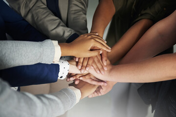 Committed to doing it together. Closeup shot of a group of unrecognisable businesspeople joining their hands together in unity.