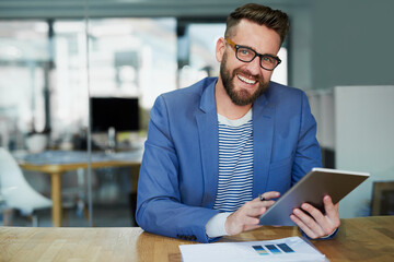 Fototapeta premium I craft all my winning concepts on this handy device. Portrait of a young businessman working on a digital tablet in an office.