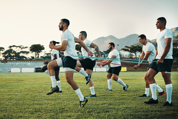They take their training sessions very seriously. Full length shot of a group of young rugby players training with bands on the field during the day.