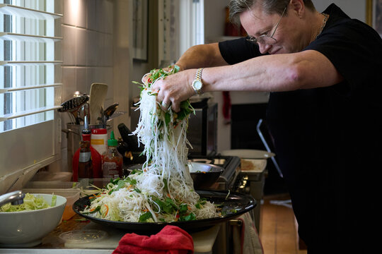 Hone cook mixing noodle salad by hand