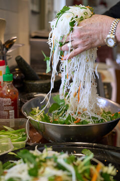 Mixing rice noodle salad by hand