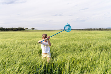 Carefree girl catching insects with net in field