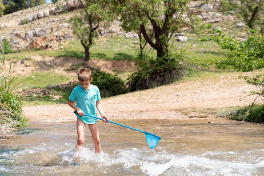 Boy catching fish in splashing shallow water