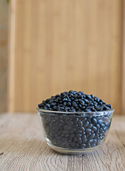 Fototapeta na wymiar Black beans in a clear glass, raw beans in a glass bowl on the table. Black beans are good for health. It is a source of protein, fiber, and disease-fighting antioxidants. Many vitamins and minerals