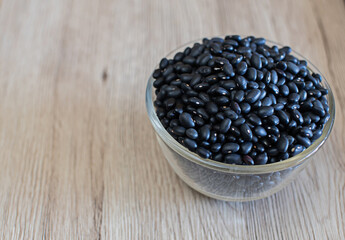 Black beans in a clear glass, raw beans in a glass bowl on the table. Black beans are good for health. It is a source of protein, fiber, and disease-fighting antioxidants. Many vitamins and minerals