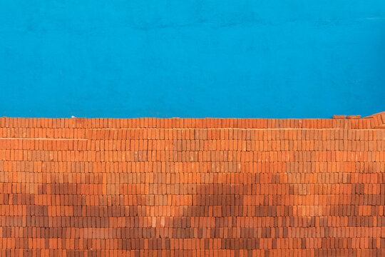Stacked bricks in front of a blue colored wall 