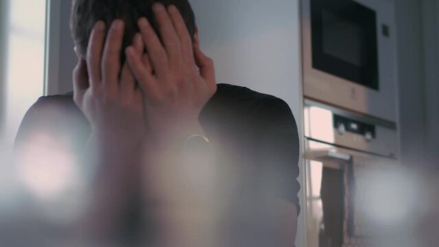Man rubs his hands through his black hair in sadness and despair, Dolly shot