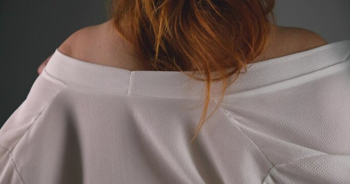 Attractive red hair woman putting on white blouse in sexual manner, back view