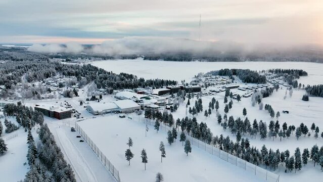 Aerial view away from the foggy Vuokatti hill, winter sunset in Finland - pull back, drone shot