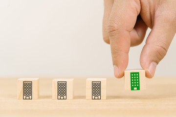 Green and eco home concept.a man hand holds the wooden cubes with green building symbols