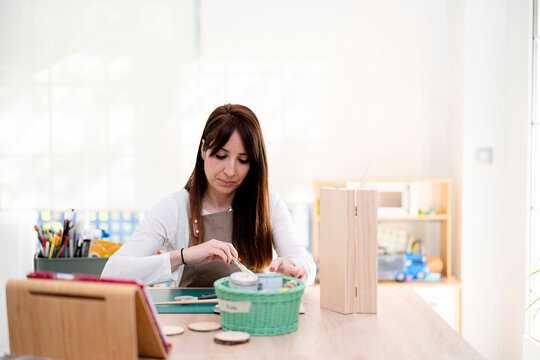 Woman watching tablet and painting on wooden details