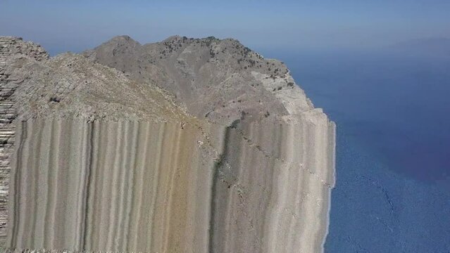 Orbiting aerial of climbers on craggy rock summit of Mt Dikeos, Greece