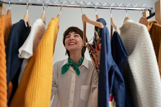 Happy woman choosing sweater at home