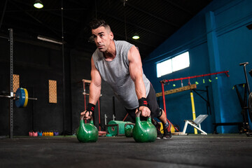 Adult athlete doing push ups on kettlebells