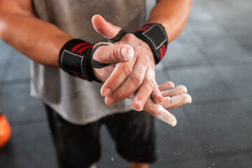 Crop athlete clasping powdered hands