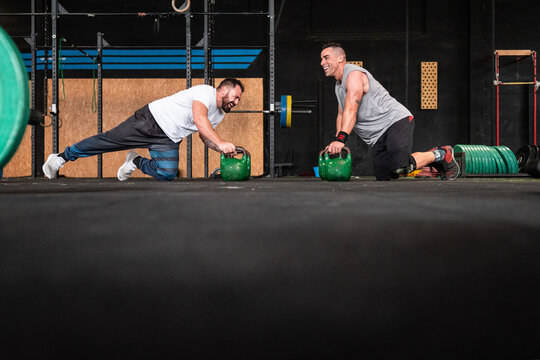 Adult men athlete friends doing push ups on kettlebells